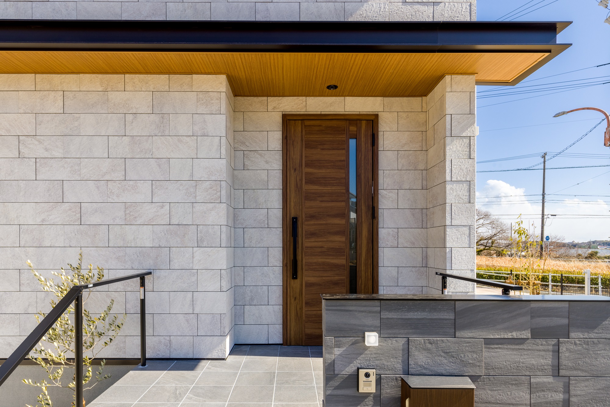 統一感と高級感をもたらす門塀と調和した石貼りのアプローチ