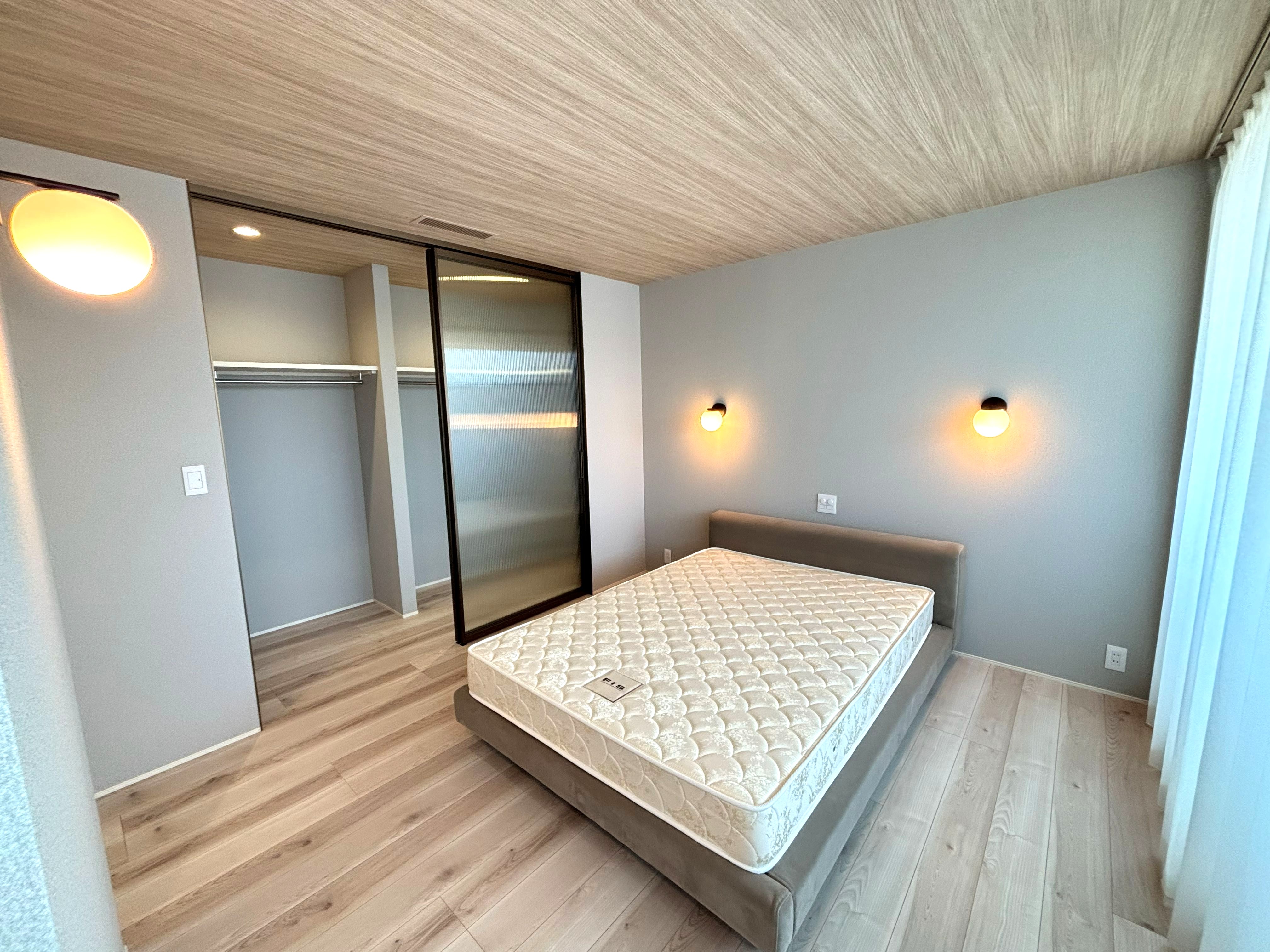 木目天井とクリア建具が映える、淡い色で統一された美しい寝室